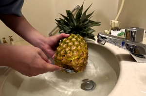 ホテルの洗面台で歯ブラシを使ってパイナップルを水洗い